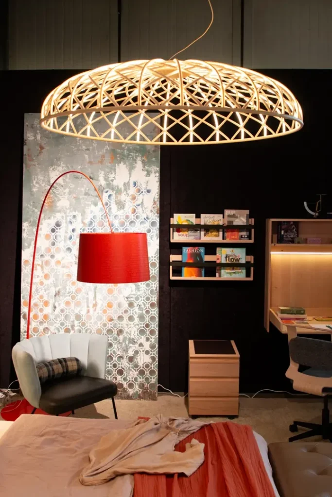 Ausstellung eines Wohnraums mit Bett, Sessel einer roten Lampe und einen Schreibtisch, im Hintergrund erkennt man eine atmende Wand mit Schablonentechnik