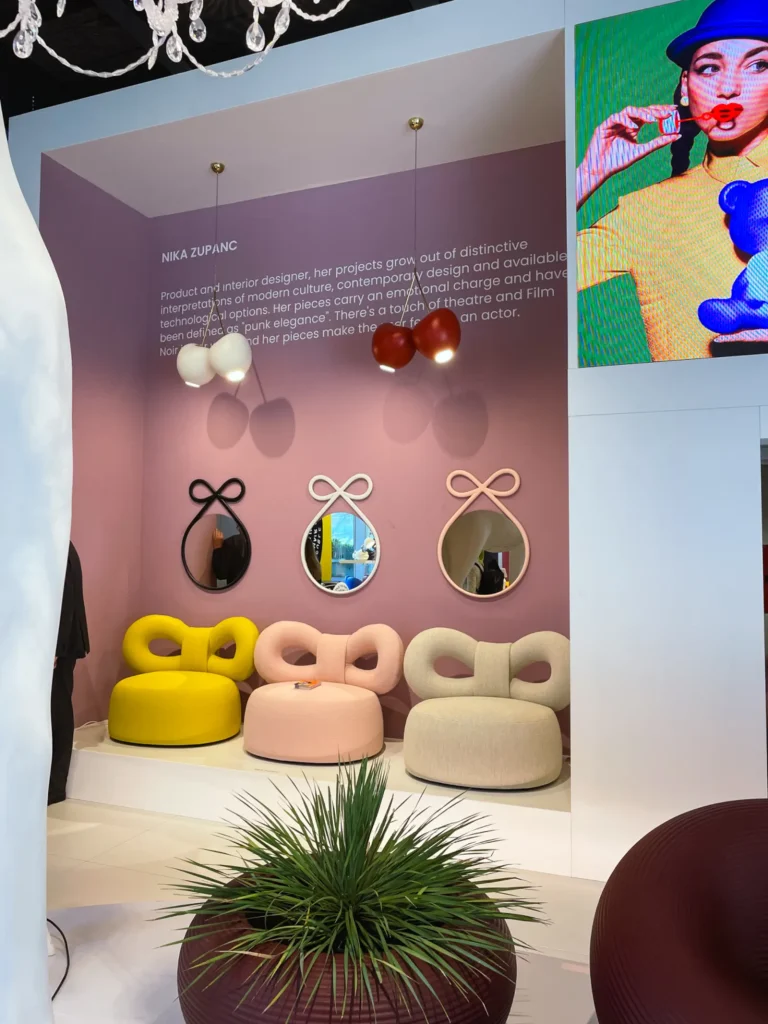 Drei Sessel in gelb, rosa und beige mit Schleifen Lehne vor einer altrosernen Wand mit drei Spiegeln darauf