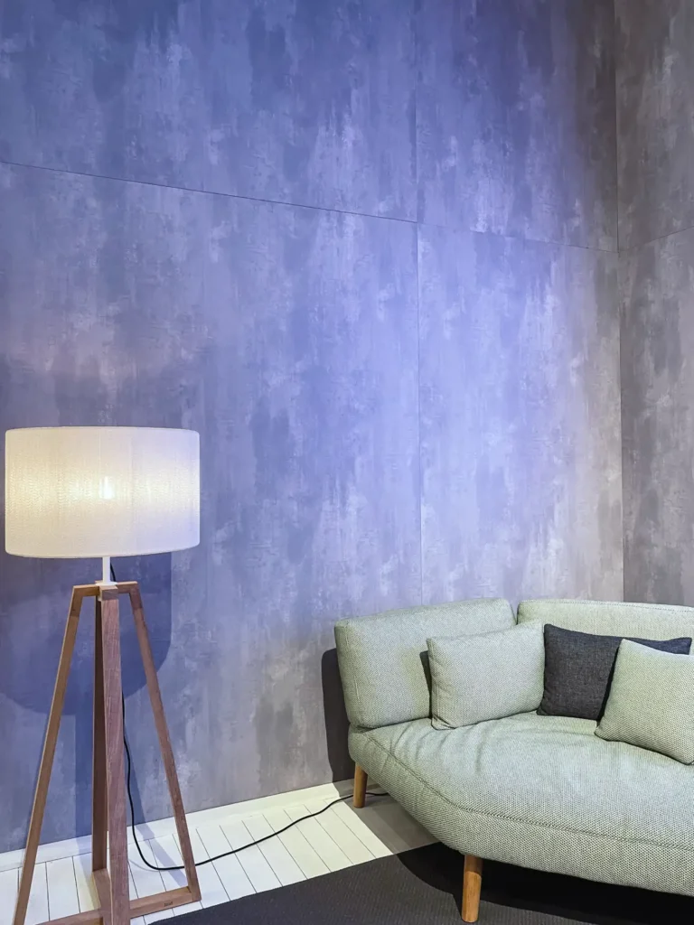 Couch und Stehlampe vor einer lilanen Wand