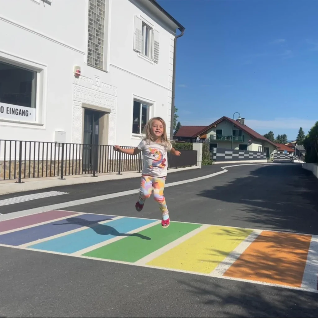 kleines Mädchen das auf einen bunten Zebrastreifen hüpft