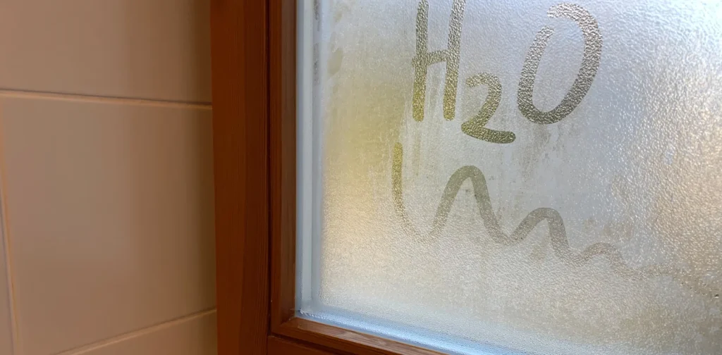 Beschlagenes Fenster mit der Inschrift H2O